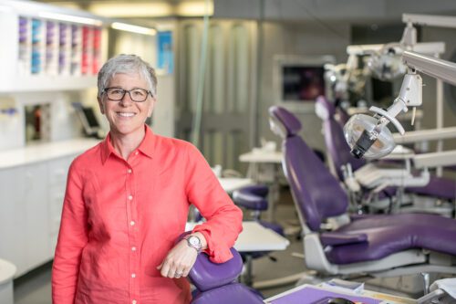 A woman standing in front of a dental chair.