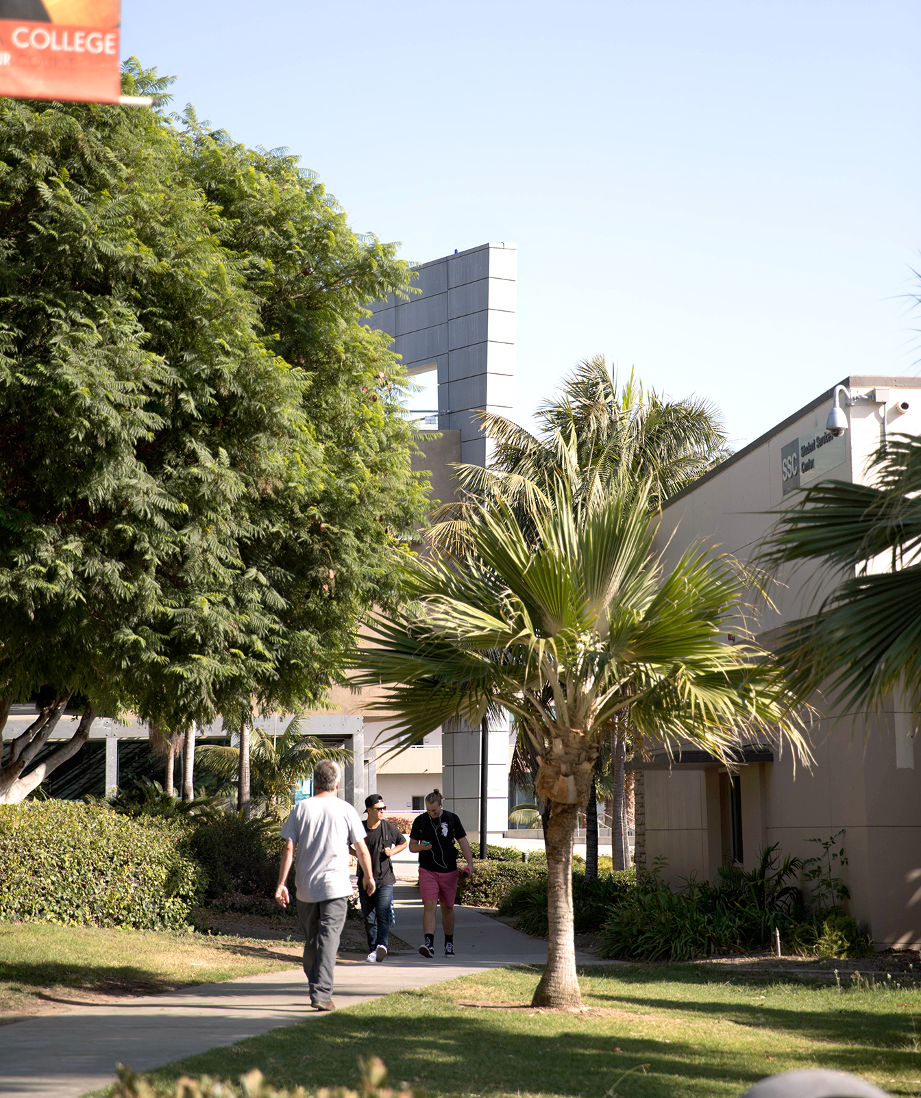 A group of people walking down a sidewalk in front of a building.