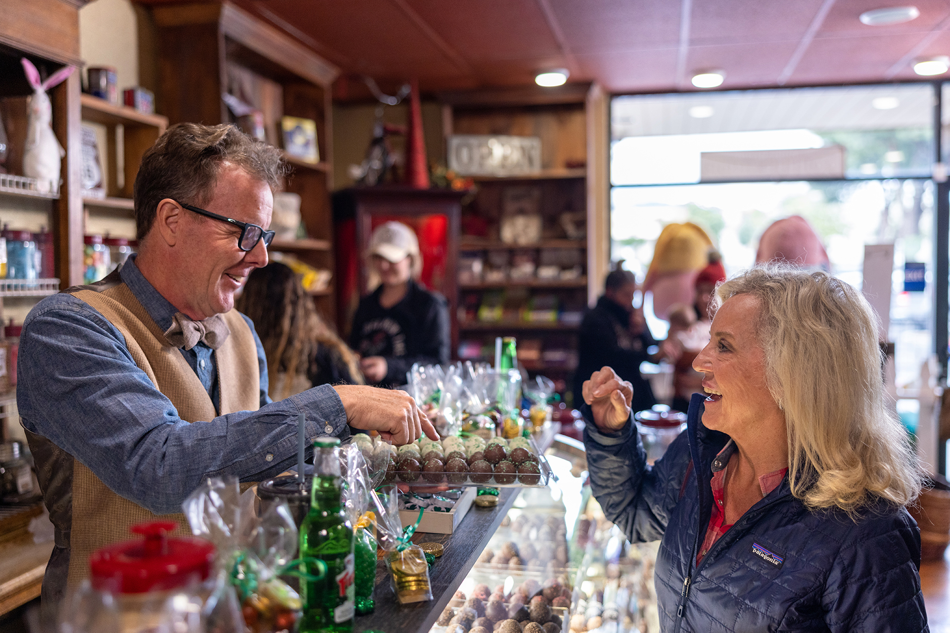 A man and woman standing at a counter in a candy store.